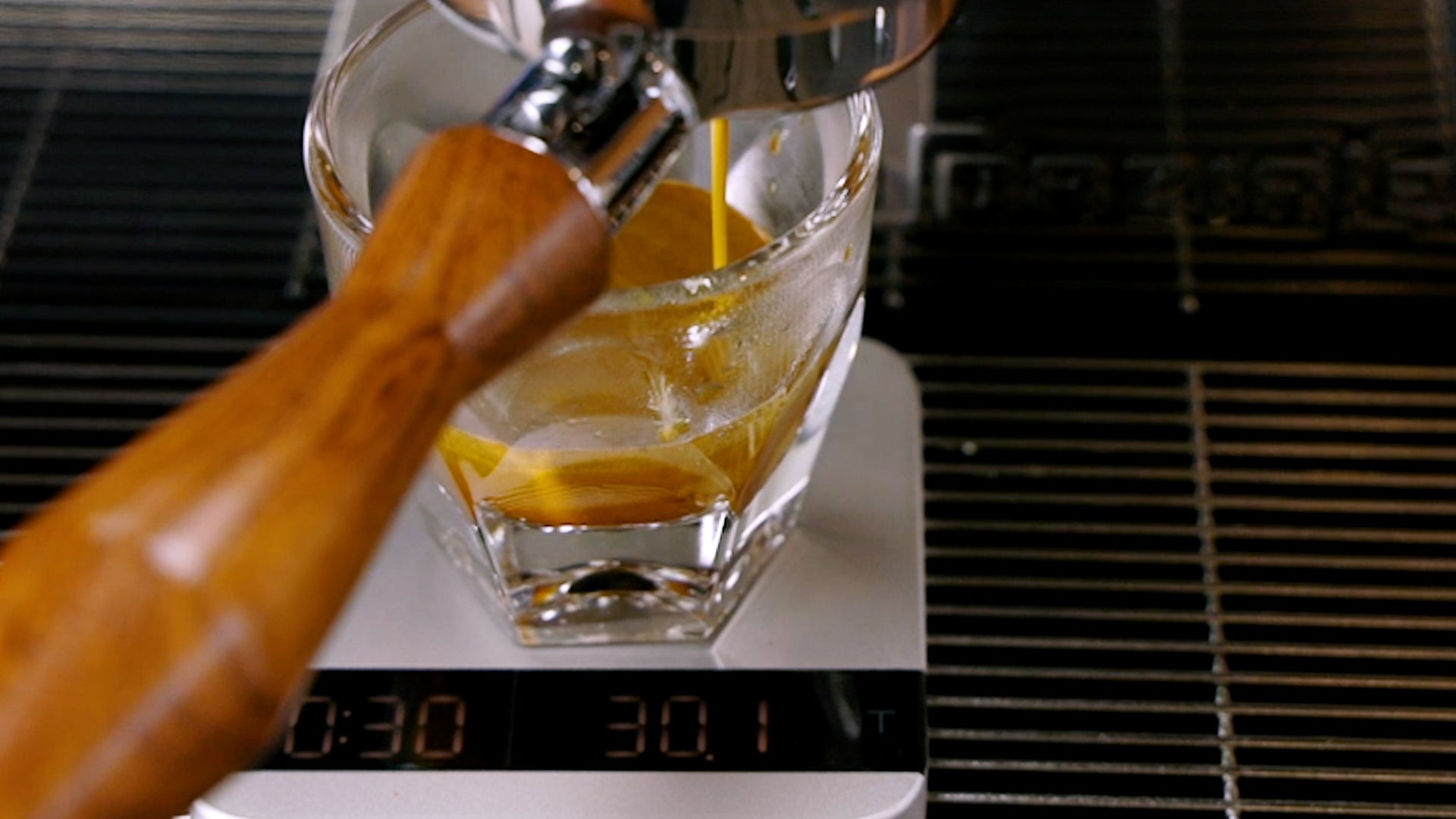 Shot of espresso pulling into a notNeutral cup on a silver acaia lunar scale featuring Clive's wood bottomless portafilter